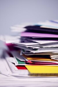 stack of colored folders overflowing with papers