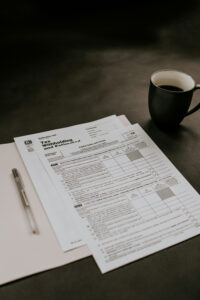 tax forms on a table with a pen and cup of coffee